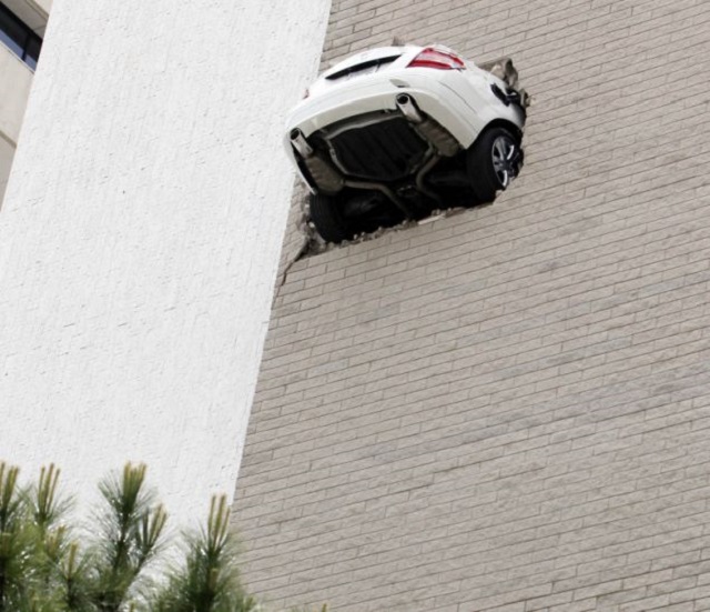 A car is seen after going through the wall on the 6th floor of a parking garage in Tulsa, Okla. on Wednesday April 28, 2010. No injuries were reported. (AP Photo/Tulsa World, Tom Gilbert)